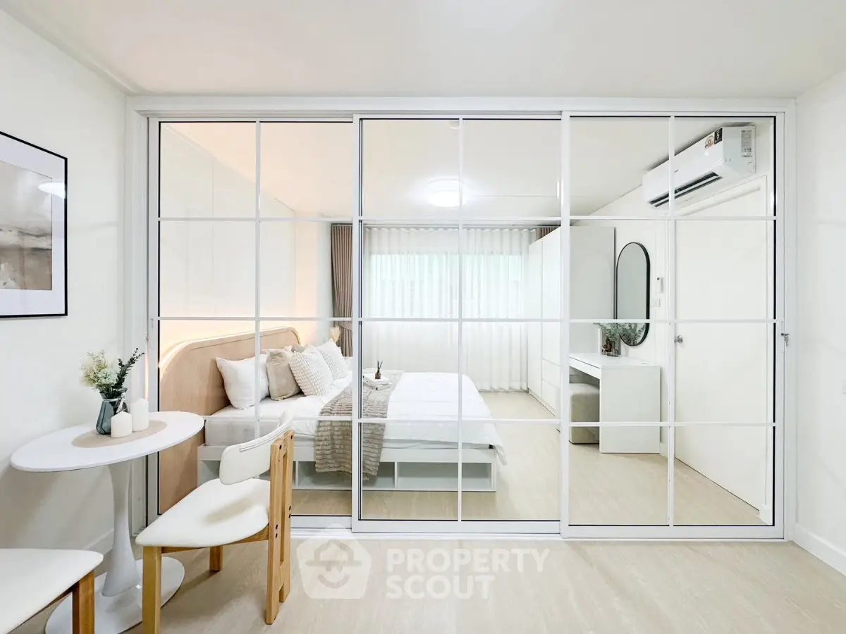 Modern bedroom with glass partition and stylish decor in a cozy apartment.