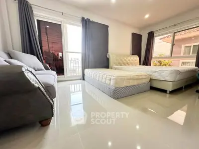 Spacious bedroom with two beds and large windows offering natural light.