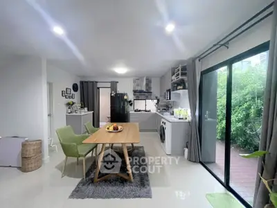 Modern open-plan kitchen and dining area with garden view, featuring sleek appliances and stylish decor.