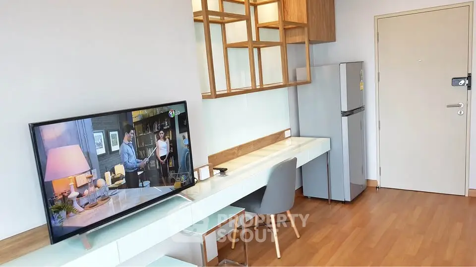 Modern living room with stylish TV setup and sleek fridge, featuring wooden flooring and contemporary decor.