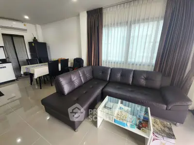 Spacious modern living room with sleek leather sofa and dining area, perfect for urban living.
