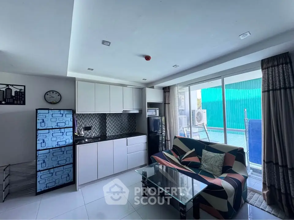 Modern living room with sleek kitchen and pool view, featuring stylish decor and natural light.