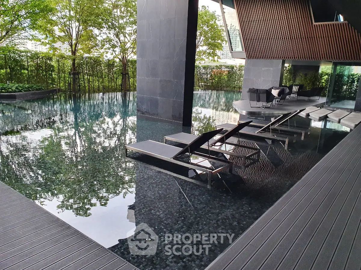 Luxurious modern pool area with sleek lounge chairs and lush greenery, perfect for relaxation.