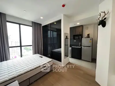 Modern studio apartment with sleek kitchen and large windows offering city views.