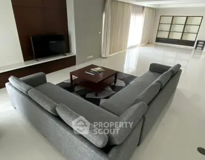 Spacious modern living room with sleek gray sectional sofa and large windows.
