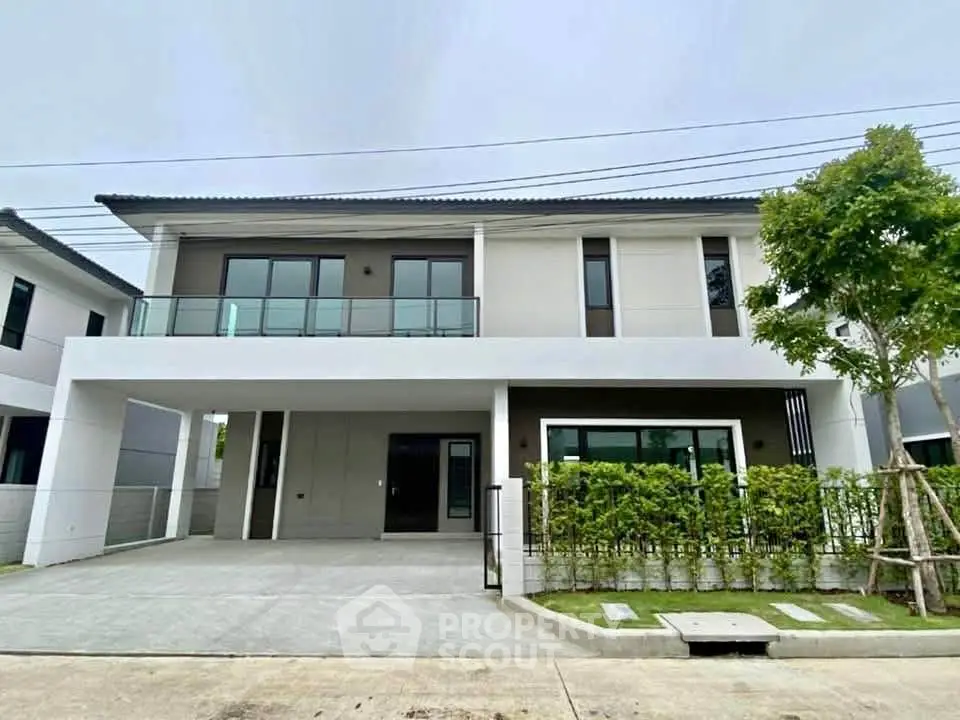 Modern two-story house with large windows and landscaped front yard in a serene neighborhood.