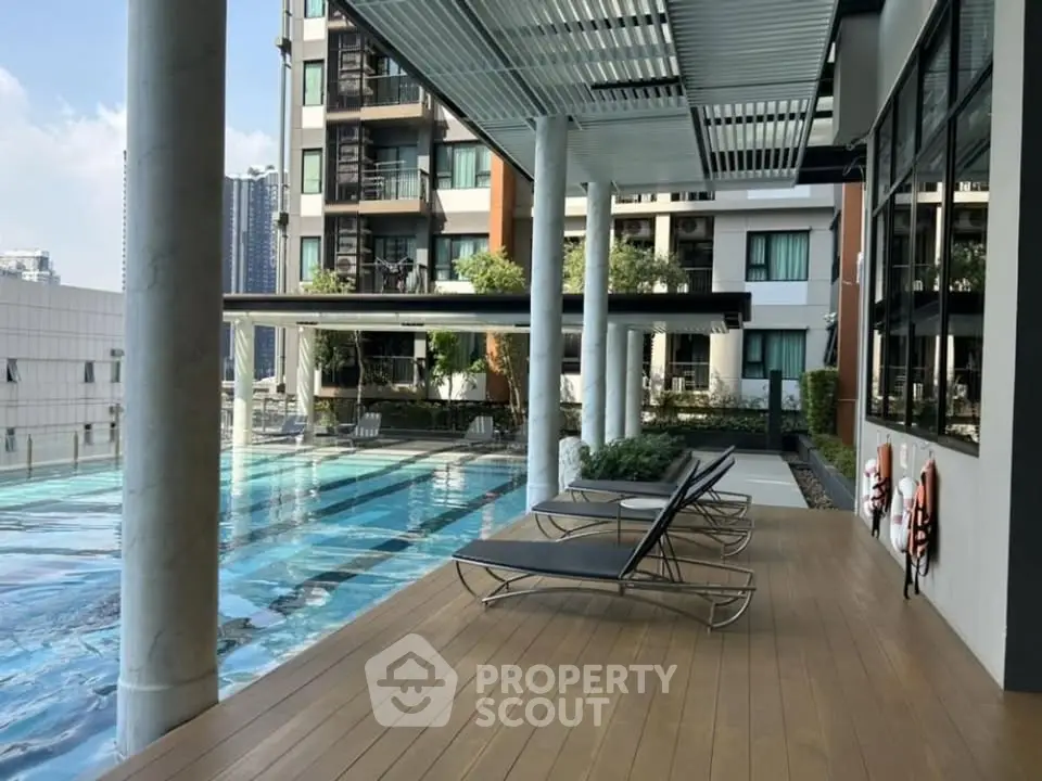 Luxurious apartment complex with modern poolside lounge area and stunning city views.