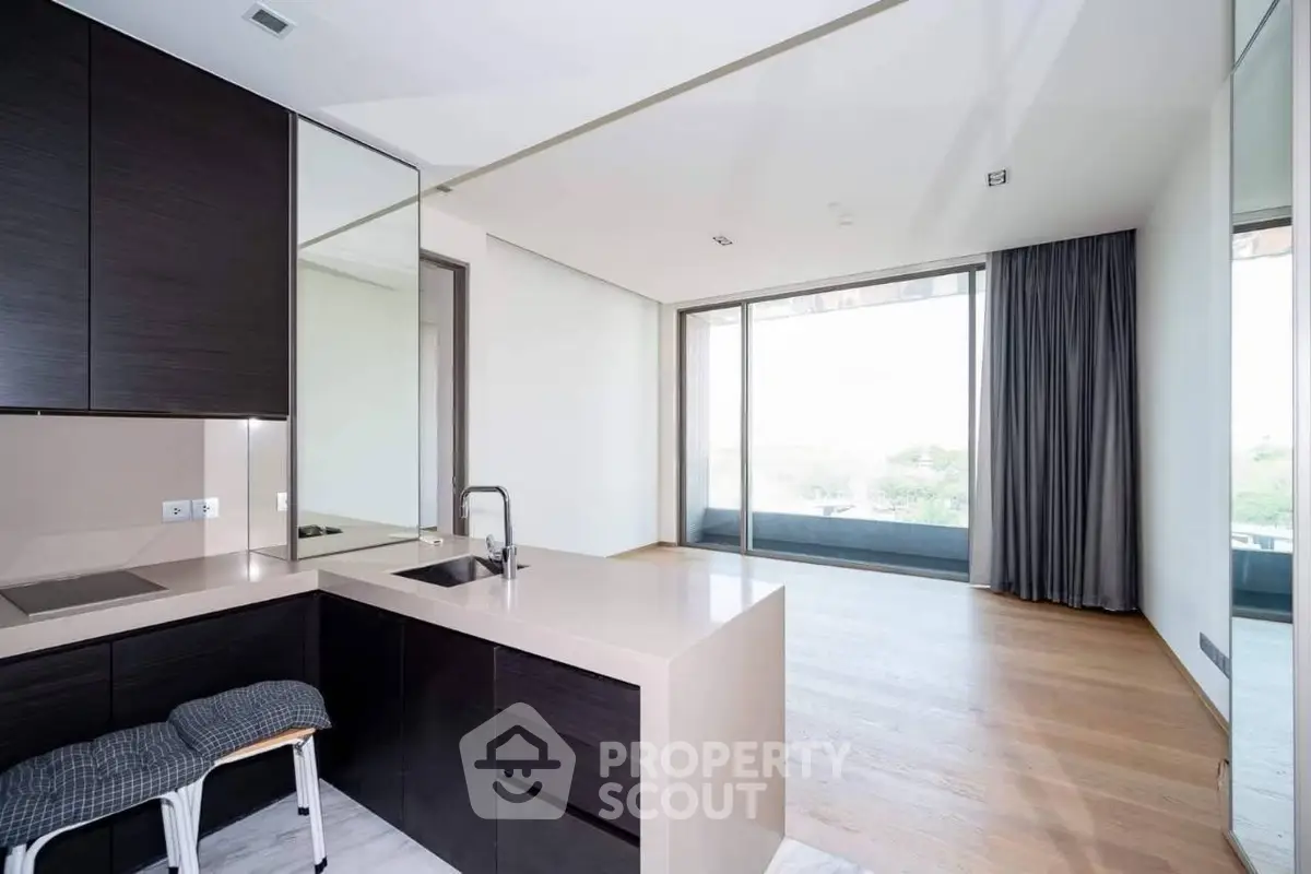 Modern open-plan kitchen with sleek design and large windows offering natural light and scenic views.