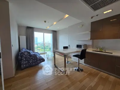 Modern open-layout living room with kitchen, featuring large window and stylish furnishings.