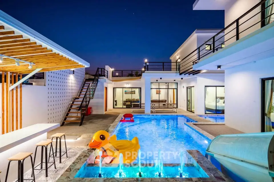 Luxurious modern villa with stunning pool and outdoor seating at night.