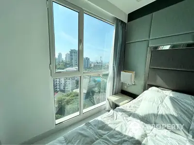 Modern bedroom with large window offering stunning city view, featuring elegant decor and natural light.