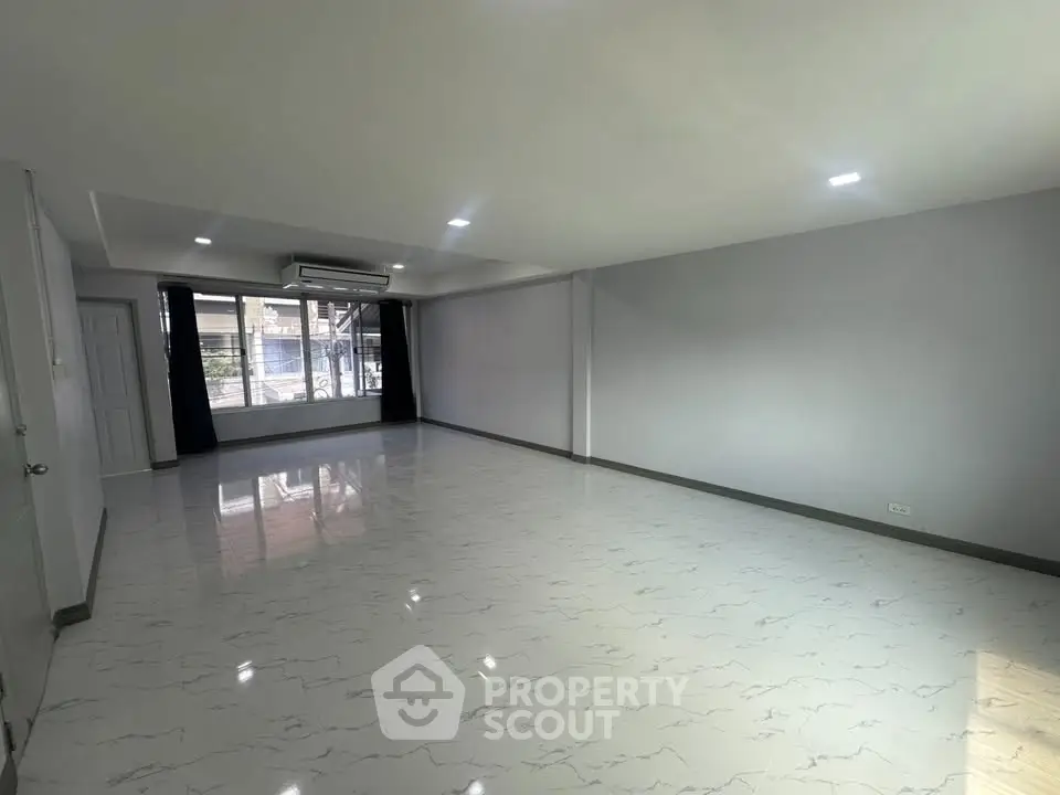 Spacious unfurnished living room with large windows and glossy tiled floor
