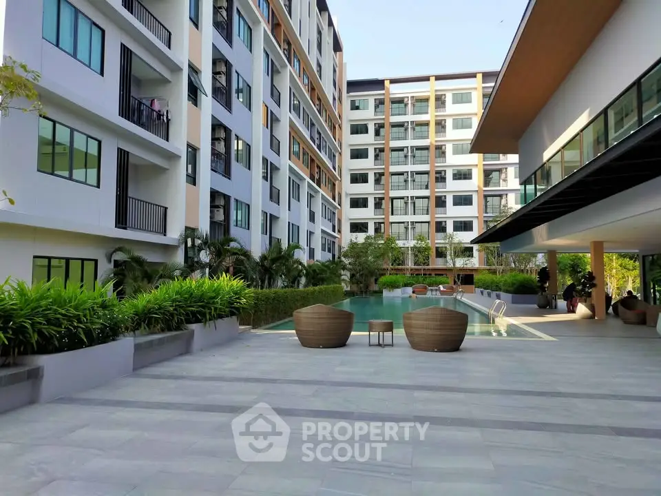 Modern apartment complex with pool and outdoor seating area, showcasing contemporary architecture and lush landscaping.