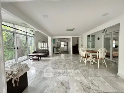 Spacious open-plan living area with marble flooring and large windows.