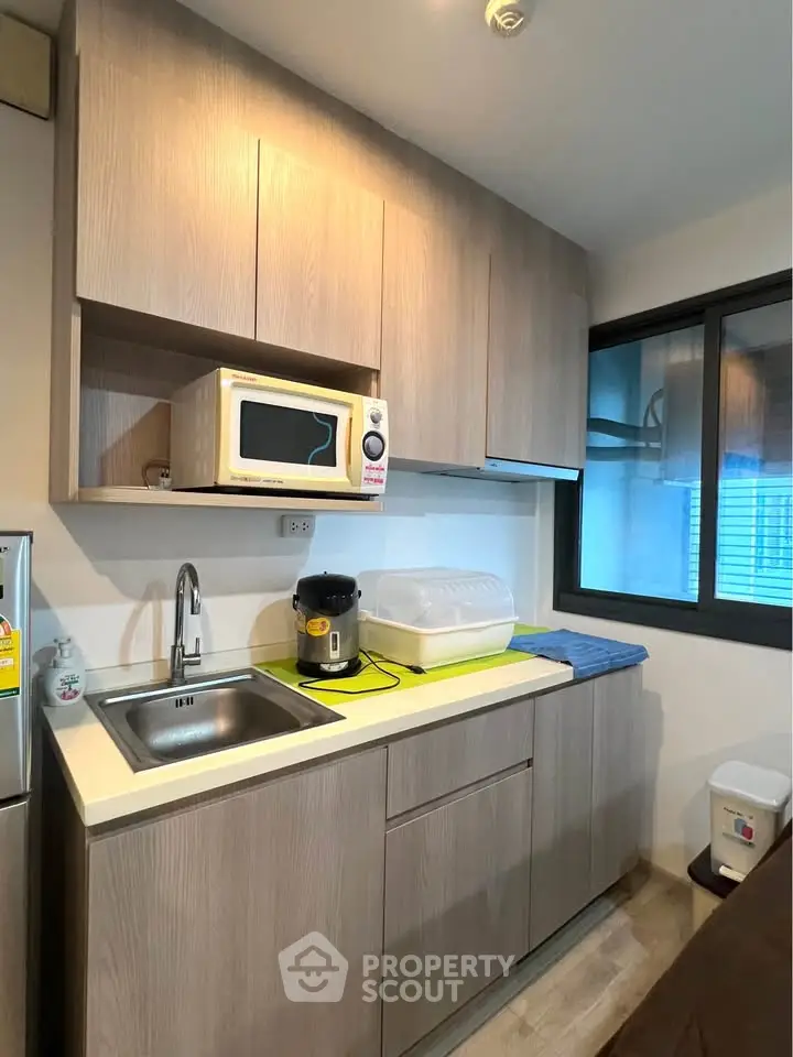 Modern compact kitchen with microwave and sleek cabinetry in cozy apartment