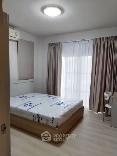 Modern bedroom with natural light, featuring a bed, curtains, and a sleek desk.