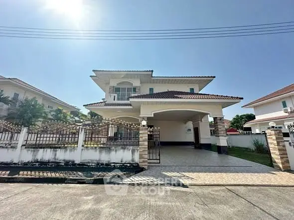 Spacious two-story house with a tiled roof and gated driveway in a sunny suburban neighborhood.