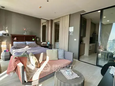 Modern studio apartment with cozy bed and stylish decor, featuring a compact kitchen and city view.