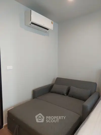 Cozy bedroom with modern air conditioning and stylish gray sofa bed.