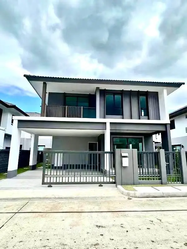 Modern two-story house with sleek design and spacious driveway under a cloudy sky.