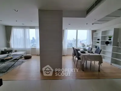 Spacious modern living and dining area with city view, featuring elegant decor and natural light.