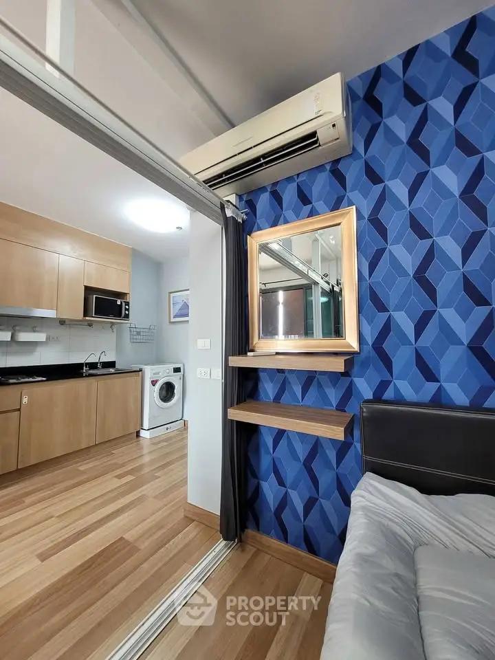 Modern apartment interior with stylish kitchen and cozy bedroom featuring geometric blue accent wall.