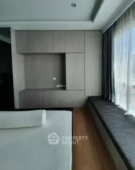 Modern bedroom with sleek built-in storage and large window seating area.
