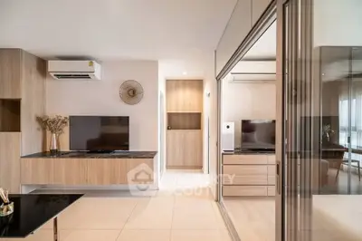 Modern living room with sleek design and large TV, featuring wooden accents and air conditioning.