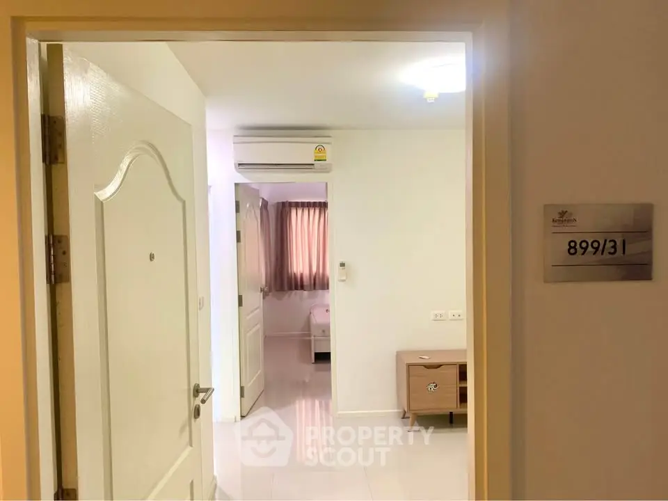 Cozy apartment entrance with view into a bright bedroom featuring air conditioning and modern furnishings.