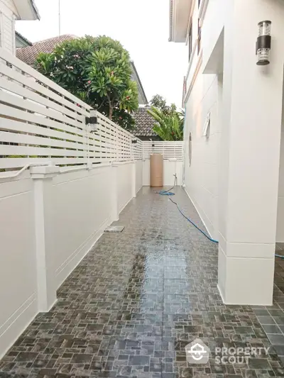 Inviting pathway in a serene residential setting with a modern white fence and lush greenery, leading to a secure and private living space.