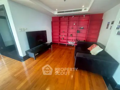 Spacious living room with sleek wooden flooring and modern red shelving unit.