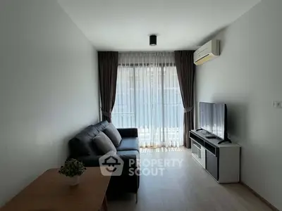 Modern living room with sleek furniture and natural light from large window.