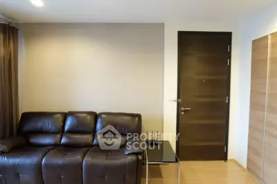 Modern living room with leather sofa and wooden door, ideal for cozy urban living.