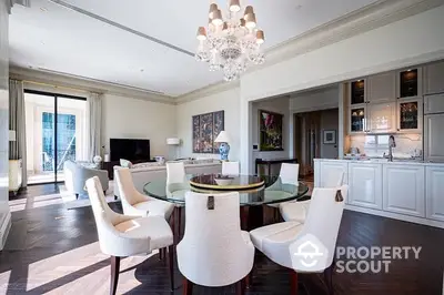 Elegant open-plan living space with gleaming hardwood floors, a modern kitchen, and a chic dining area, illuminated by a sophisticated chandelier.