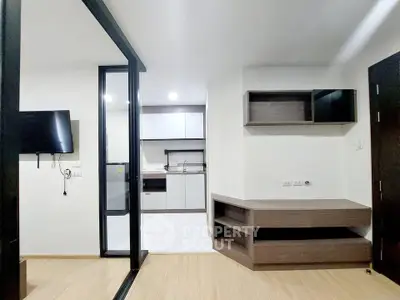 Modern apartment interior with open layout kitchen and living area, featuring sleek cabinetry and wood flooring.