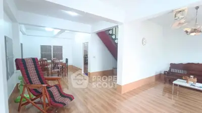 Spacious living room with wooden flooring and modern furniture in a bright, open layout.