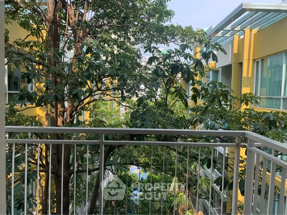 Lush garden view from a balcony in a modern apartment complex with vibrant yellow accents.