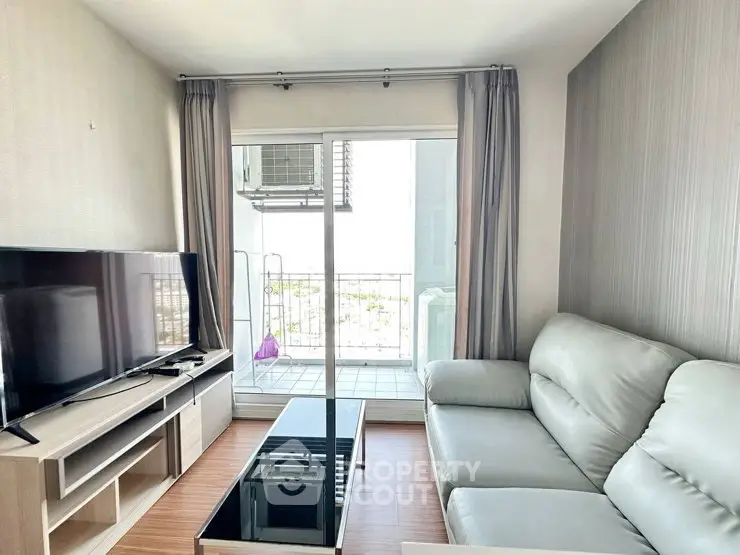 Modern living room with balcony view, featuring sleek furniture and natural light.