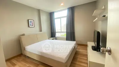 Modern bedroom with large window and sleek furnishings in a high-rise apartment.