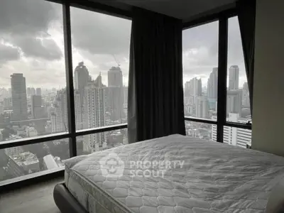 Luxurious bedroom with panoramic city view from floor-to-ceiling windows in a high-rise apartment.