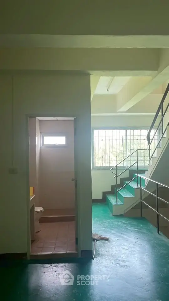 Spacious stairwell with natural light and adjacent bathroom in modern building.