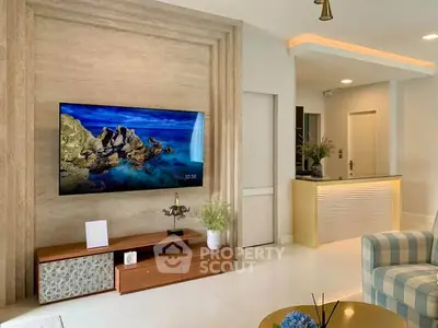 Modern living room with stylish decor and wall-mounted TV, featuring sleek furniture and ambient lighting.