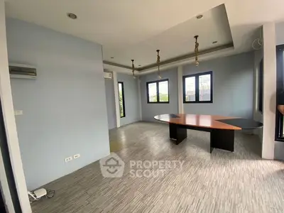 Spacious modern room with unique table and large windows offering natural light.