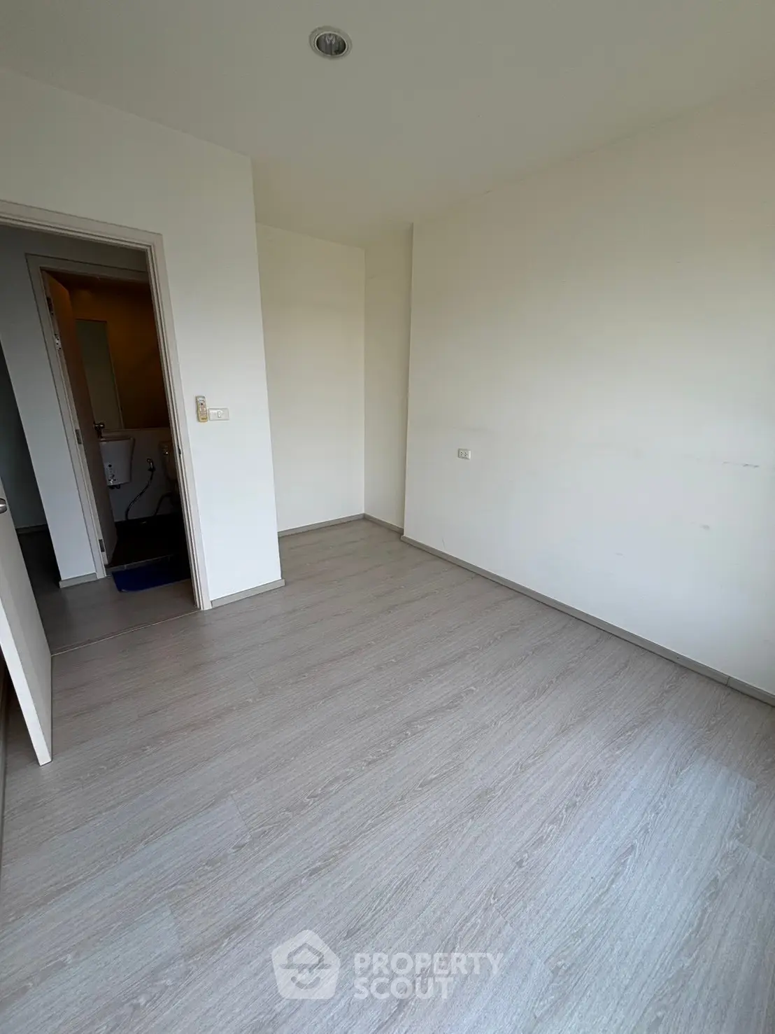 Spacious empty room with light wood flooring and white walls, ready for customization.