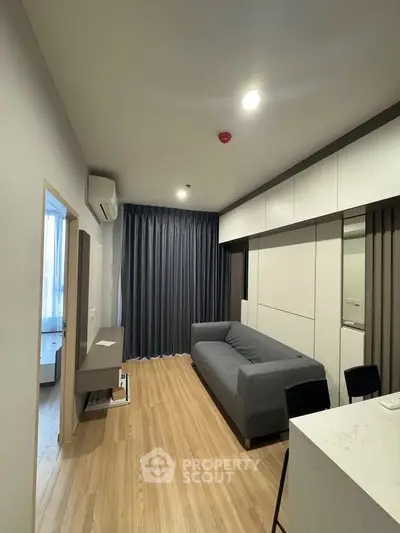 Modern living room with sleek design, featuring a gray sofa, wooden flooring, and elegant curtains.
