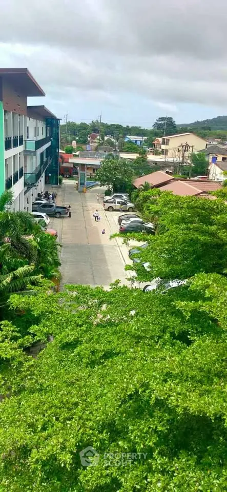 Aerial view of residential area with lush greenery and parked cars, showcasing urban living.