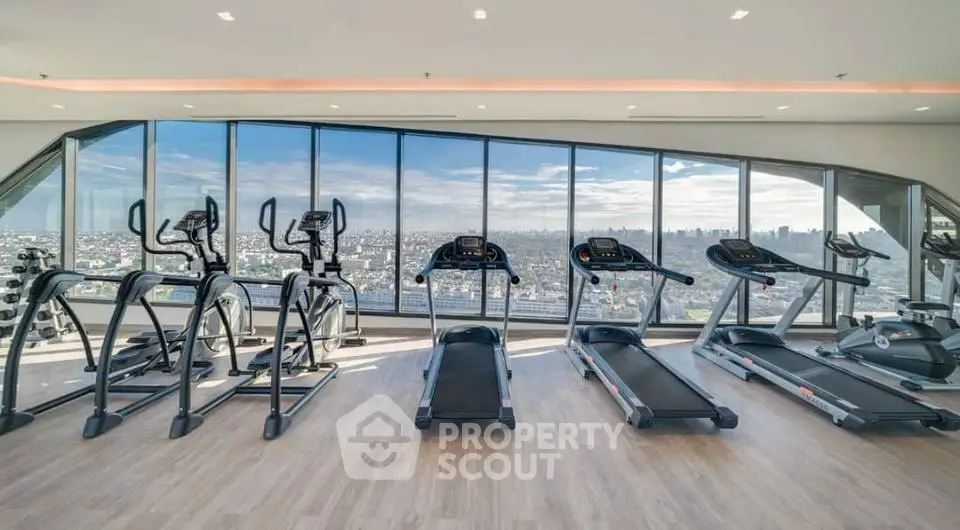 Luxurious high-rise gym with panoramic city views and modern fitness equipment.