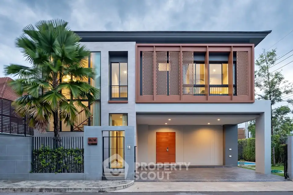 Modern two-story house with sleek design and large windows, featuring a spacious garage and lush greenery.