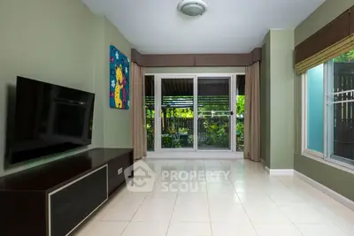 Spacious living room with large windows and garden view, perfect for relaxation and entertainment.