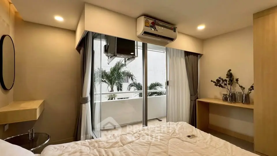 Modern bedroom with balcony access and air conditioning, featuring elegant decor and natural light.